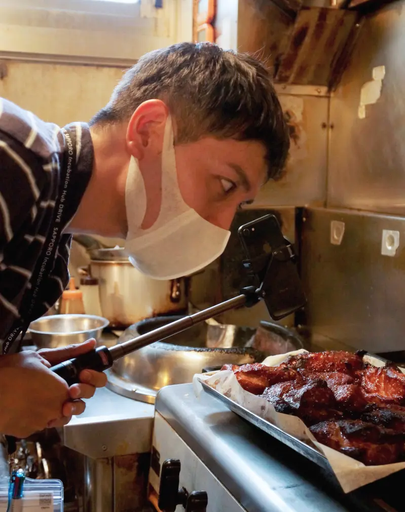 焼き上がったチャーシューをのぞき込む猪飼さん