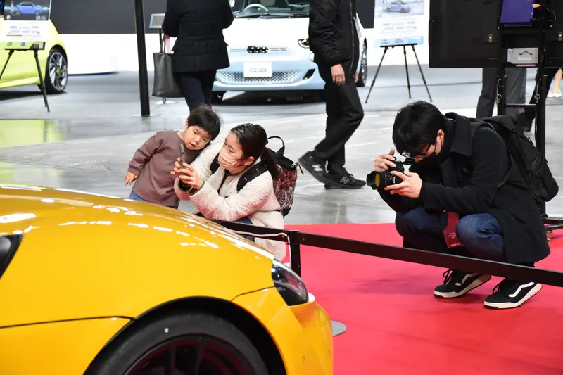 展示車両にカメラを向けるイベント参加者